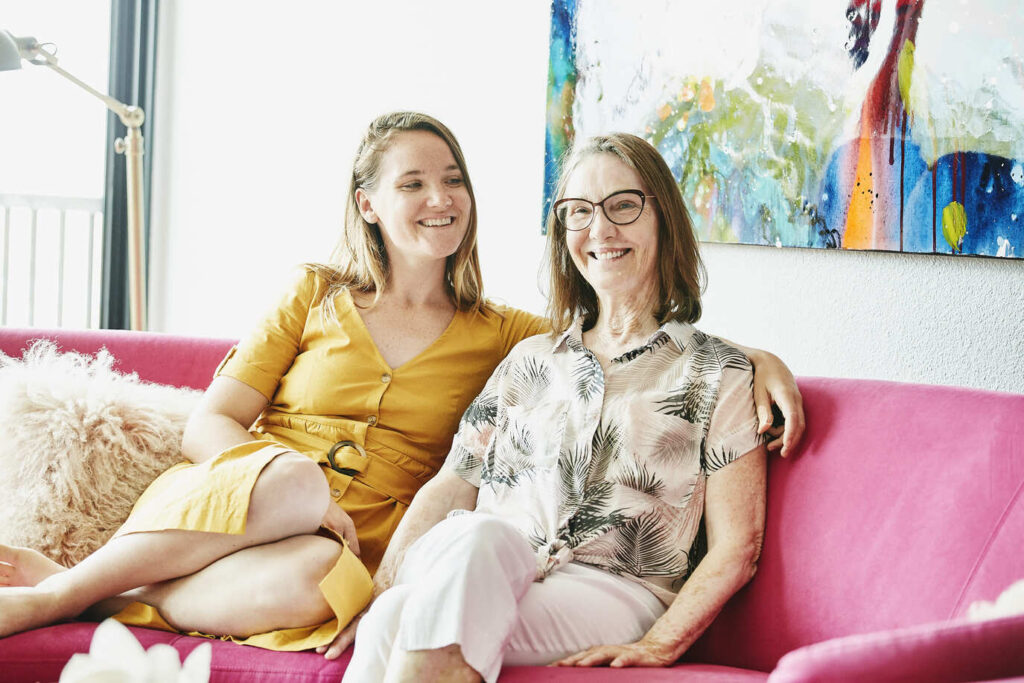 Two women on a sofa smiling.