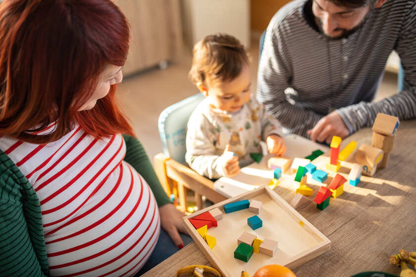 A pregnant woman and her child playing with building blocks