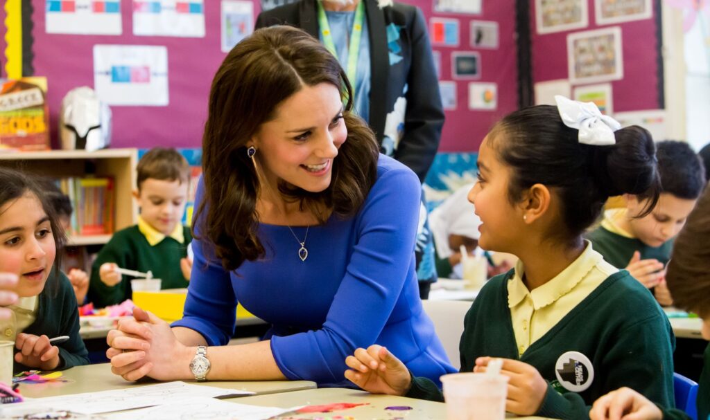 The Princess of Wales talking with a young girl at a school.
