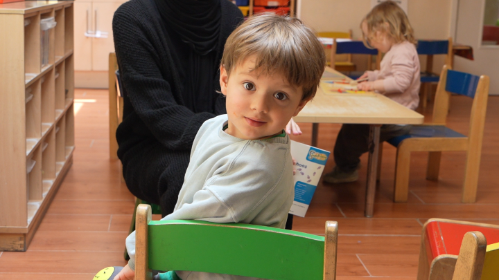 Young boy sat in a chair looking into the camera with a smile.